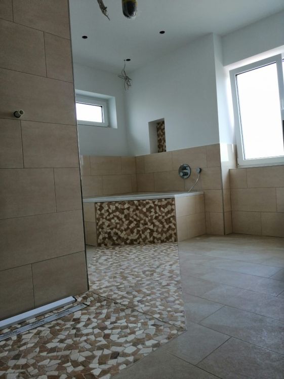beigefarbenes Badezimmer mit Mosaikfliesen. Das Badezimmer hat eine große Badewanne